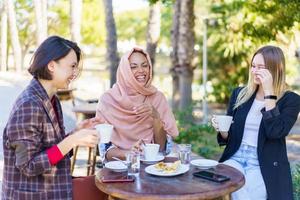 vrolijke multiraciale vrouwen die op terras zitten foto