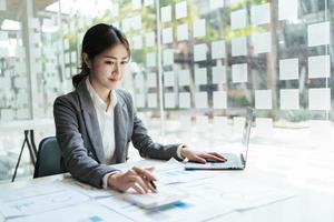 Aziatische accountantsvrouw die over financieel met bedrijfsrapport en calculator.financial of boekhoudingsconcept werkt. foto