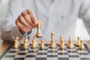 zakenman hand bewegende gouden schaakkoning figuur en schaakmat tegenstander tijdens schaakbord competitie. strategie, succes, management, bedrijfsplanning, disruptie en leiderschapsconcept foto