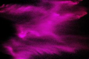 roze deeltje stof splash op zwarte achtergrond. roze poeder explodeert. foto