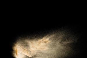 bruin gekleurde zandplons tegen een donkere achtergrond. droge rivier zand explosie geïsoleerd op zwarte achtergrond. abstracte zandwolk. foto