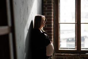 portret van een zwanger meisje bij het raam foto