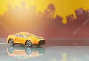 oranje sedan auto speelgoed selectieve focus op wazige stadsachtergrond foto
