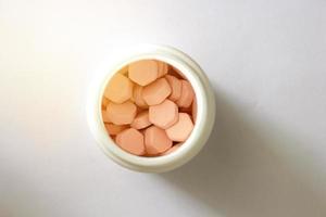 zeshoekige tabletten in witte plastic pot in drogisterijconcept voor medische gezondheidszorg, gesloten foto