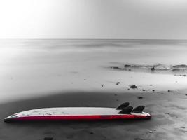 surfplank achtergelaten op het strand in de winter foto