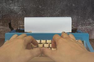 zakenman handen typen op een oude schrijfmachine op houten bureau. foto