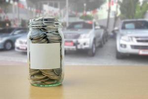 geld in de glazen fles met autoshowroom achtergrondvervaging foto