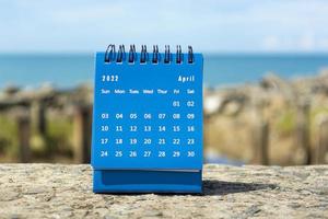 blauwe april 2022 kalender op onscherpe achtergrond van blauwe oceaan foto