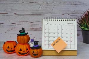 witte oktober 2022 kalender met jack o lantern pompoen op houten bureau. foto