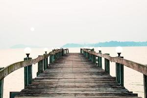 een houten loopbrug die zich uitstrekt in de zee. vakantie reisconcept foto