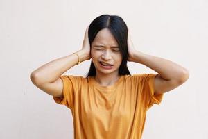 vrouw bedekte zijn oren over grijze achtergrond foto