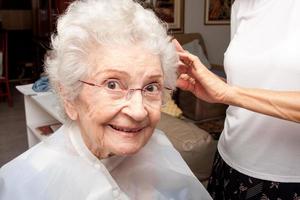oudere dame wordt geknipt in het comfort van haar huis foto