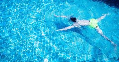 mannen zwemmen of duiken in het zwembad. jonge man trainen of ontspannen in het buitenzwembad. foto