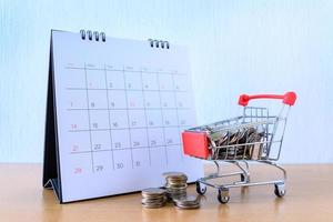 kalender met dagen en kar supermarkt op houten tafel. winkelconcept foto