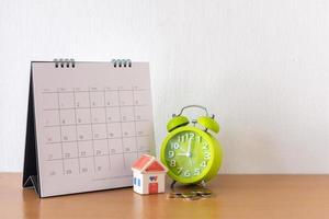 kalender en huis op tafel. dag van aan- of verkoop van een huis of betaling voor huur of lening. foto
