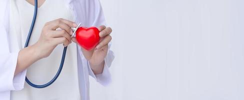 arts die met stethoscoop rood hart onderzoekt foto