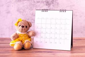 teddybeer met kalender op houten tafel. valentijnsdag viering foto