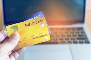 man met creditcard op laptop. online winkelen op internet met een laptop foto