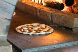 dunne korst pizza bakken in houtgestookte oven foto