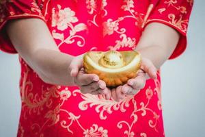 Aziatische vrouw die met cheongsam goud houdt. Chinees Nieuwjaar. foto