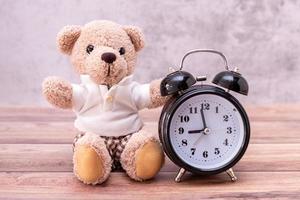 teddybeer en klok op houten tafel. valentijnsdag viering foto