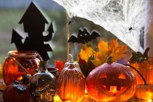feestelijke inrichting van het huis op de vensterbank voor halloween - pompoenen, jack-o-lantaarns, schedels, vleermuizen, spinnenwebben, spinnen, kaarsen en een slinger - een gezellige en vreselijke stemming foto