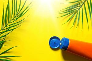 tube zonnebrandcrème op een gele zomerachtergrond met palmbladeren en de zon. looimiddel, huidbescherming, een reis naar de zee, vakantie op het strand, uv-bescherming, spf-filter. plat leggen, ruimte kopiëren foto