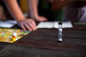 bordspelbord, chips, kubus, timer op een donkere houten tafel en handen op de achtergrond. het concept van teamwork, intellectuele ontspanning, bedrijfsevenement, thuis spelen met kinderen. kopieer ruimte foto