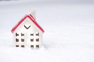 het symbool van een huis in de sneeuw met een hart is een liefdesnestje, huisvesting voor een jong gezin, comfort met een geliefde. valentijnsdag, gezellig, huisje, verhuizen, hypotheek, warm huis foto