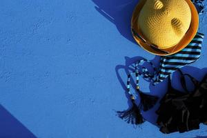 damesaccessoires voor een strandvakantie op een blauwe achtergrond. het concept van een reis naar de zee, ontspanning, zwemmen, uv-bescherming, zonnebank. toerisme- en reisbureau. plaats voor tekst. kader. flatlay foto