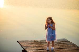 een klein meisje houdt een toetje in haar handen en wil het heel graag opeten. foto