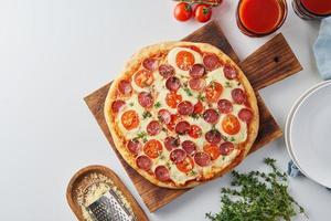 hete zelfgemaakte Italiaanse pepperoni pizza met salami, mozzarella op witte tafel foto