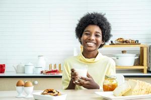 kind aan het ontbijt. gelukkige schattige Afro-Amerikaanse jongen die melk drinkt en brood eet met ei. kinderen eten op zonnige ochtend. gezonde uitgebalanceerde voeding voor jonge kinderen. foto