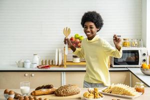 afro-amerikaanse gelukkige jongen houdt een houten lepel en brood op servies in de keuken, voor een gelukkig gezin kookgenot in huis. foto