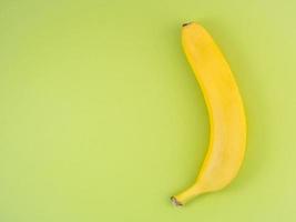 rijpe gele banaan op heldergroene achtergrond met kopieerruimte. foto
