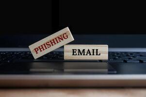 phishing e-mail tekst op houten blokken bovenop een laptop. online bedrijfsconcept foto