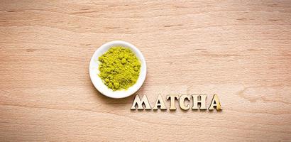 Japanse groene poeder matcha thee op een schotel, op een bruine achtergrond. inscriptie van de houten letters in het Engels. los poeder. ruimte voor tekst. koken, een ingrediënt voor een verkwikkende drank foto