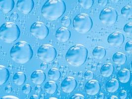 abstracte blauwe achtergrond met grote en kleine bolvormige convexe druppels water op glas. bubbels op het raam. macro, sluit omhoog. foto