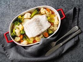 vis kabeljauw gebakken in de oven met groenten - gezonde voeding gezonde voeding. grijze stenen achtergrond, close-up, bovenaanzicht foto