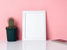 leeg wit frame en plant cactus op een witte tafel tegen de roze muur met kopieerruimte. mockup met kopie ruimte. foto