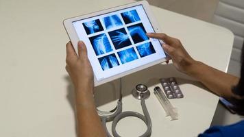 gesloten op stethoscoop en tablet met weergave van menselijke röntgenbeeldactiviteitsscan op tafel, medische werkplek. gezondheidszorg concept. foto