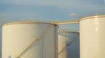 grote industriële tanks voor benzine en olie met blauwe sky.fuel-tanks op het tankpark. metalen trap aan de zijkant van een industriële oliecontainer. trap op grote brandstoftank foto