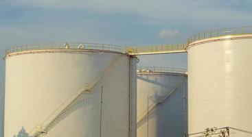 grote industriële tanks voor benzine en olie met blauwe sky.fuel-tanks op het tankpark. metalen trap aan de zijkant van een industriële oliecontainer. trap op grote brandstoftank foto