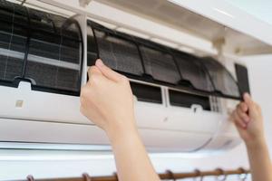 aziatische vrouw die een vuil en stoffig airconditioningfilter in haar huis schoonmaakt. huisvrouw die een stoffig airconditionerfilter verwijdert. foto