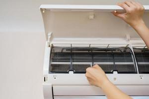 aziatische vrouw die een vuil en stoffig airconditioningfilter in haar huis schoonmaakt. huisvrouw die een stoffig airconditionerfilter verwijdert. foto