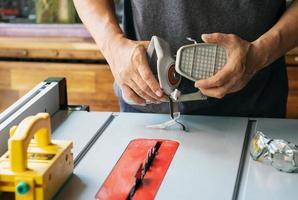 timmerman met ademhalingspatroonfilter in de buurt van cirkelzaagtafel in werkplaats foto