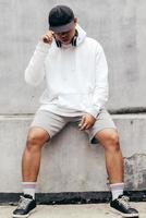 mockup van een man met een pullover-hoodie die op een betonnen muur staat en ligt foto