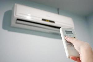 hand met afstandsbediening gericht op de airconditioner foto