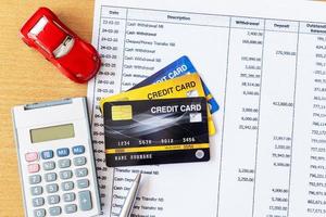 automodel en rekenmachine op bankafschrift en creditcard op een houten tafel. foto