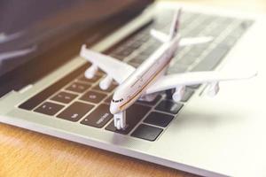 laptopcomputer en vliegtuig op tafel. online ticketboekingsconcept foto